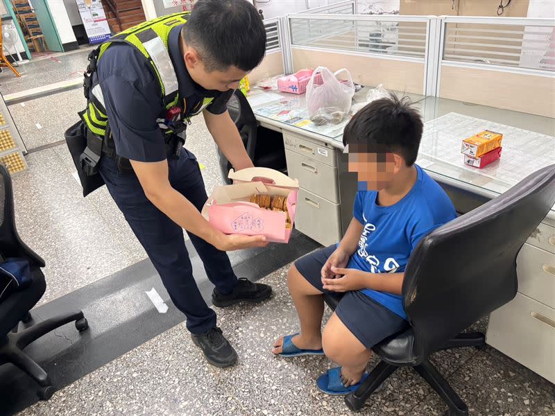 員警拿餅乾等零食給走失的陳小弟吃，安撫他情緒。（圖／警方提供）
