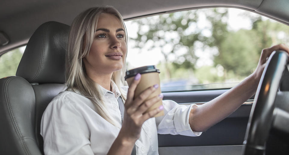 Woman driving with a coffee. Source: Getty Images