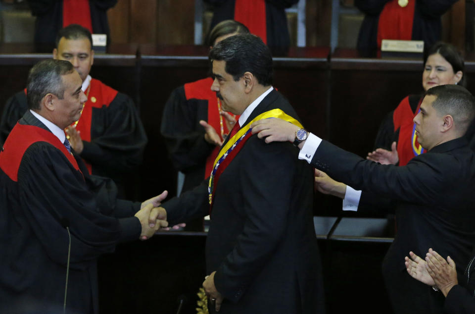 Venezuela's President Nicolas Maduro, center, shakes hands with Supreme Court President Maikel Moreno as his presidential sash is adjusted, after he took the oath of office in Caracas, Venezuela, Thursday, Jan. 10, 2019. Maduro's second, six-year term starts amid international calls for him to step down and a devastating economic crisis. (AP Photo/Ariana Cubillos)