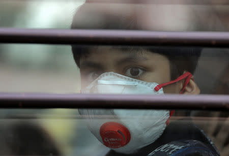 A schoolboy wearing a protective mask looks on from the inside of a school bus at Silver Line Prestige School in Ghaziabad, on the outskirts of Delhi, India, November 1, 2018. REUTERS/Anushree Fadnavis