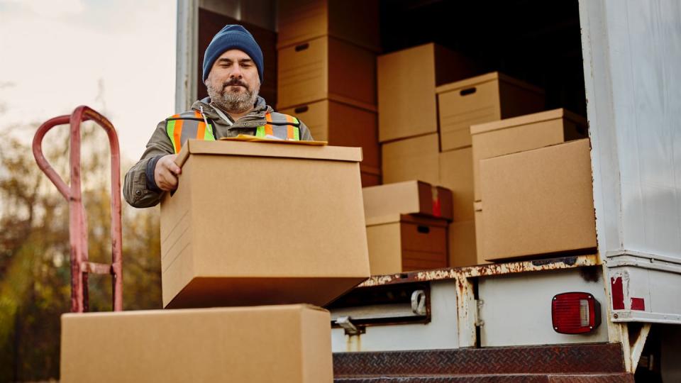 male worker unloading cardboard boxes from delivery van