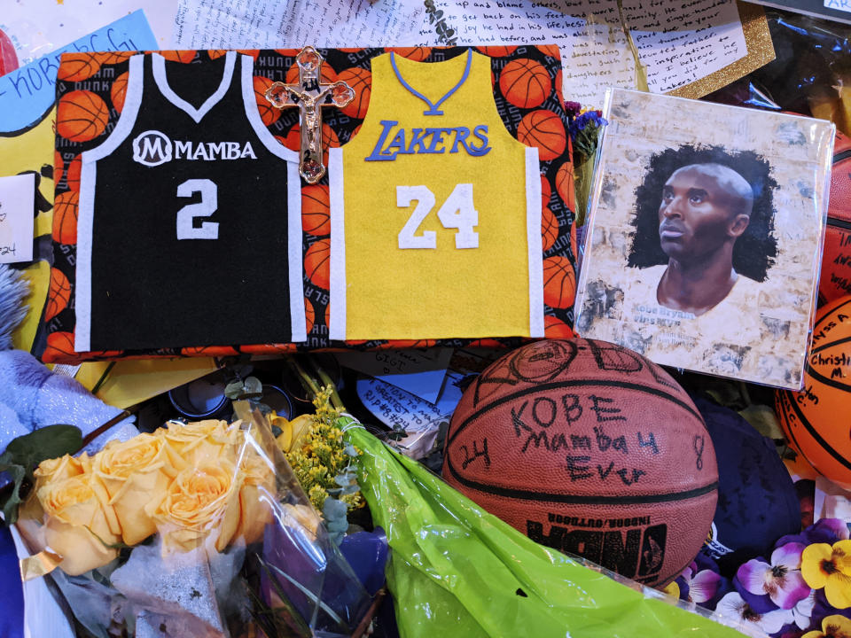 Memorabilia for NBA star Kobe Bryant are placed at a memorial for Bryant while fans gather to pay their respect near Staples Center in Los Angeles Sunday, Feb. 2, 2020. Bryant, the 18-time NBA All-Star who won five championships and became one of the greatest basketball players of his generation during a 20-year career with the Lakers, died in a helicopter crash Sunday, Jan. 26. (AP Photo/Damian Dovarganes)