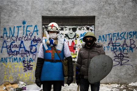 A medic of the anti-government protest camp (L) poses for a portrait with his security guard at the barricades near the site of clashes with riot police in Kiev January 28, 2014. REUTERS/Thomas Peter