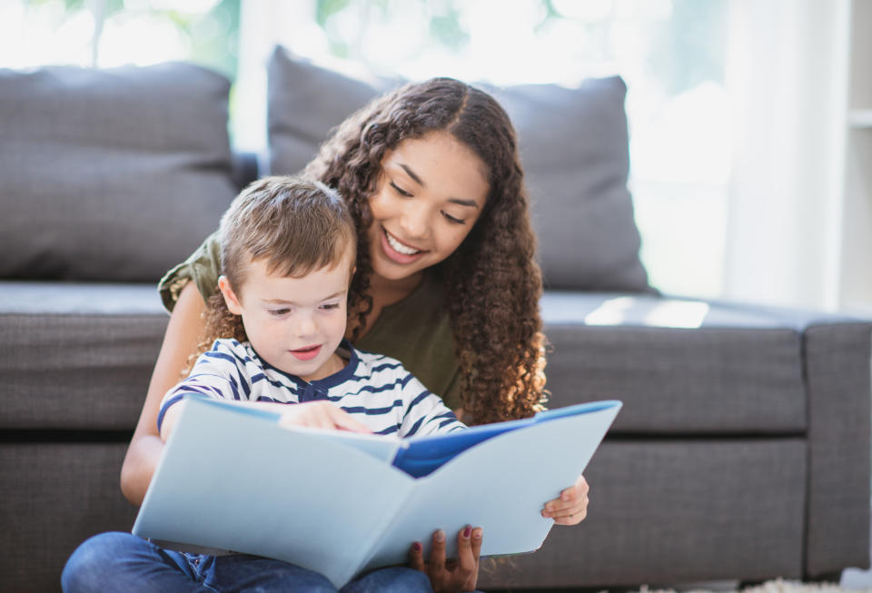 A teen girl reading with her little brother