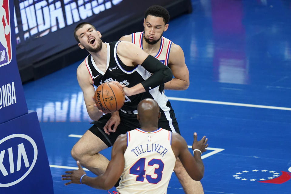 Los Angeles Clippers' Ivica Zubac center, tries to pass between Philadelphia 76ers' Ben Simmons, top, and Anthony Tolliver during the second half of an NBA basketball game, Friday, April 16, 2021, in Philadelphia. (AP Photo/Matt Slocum)