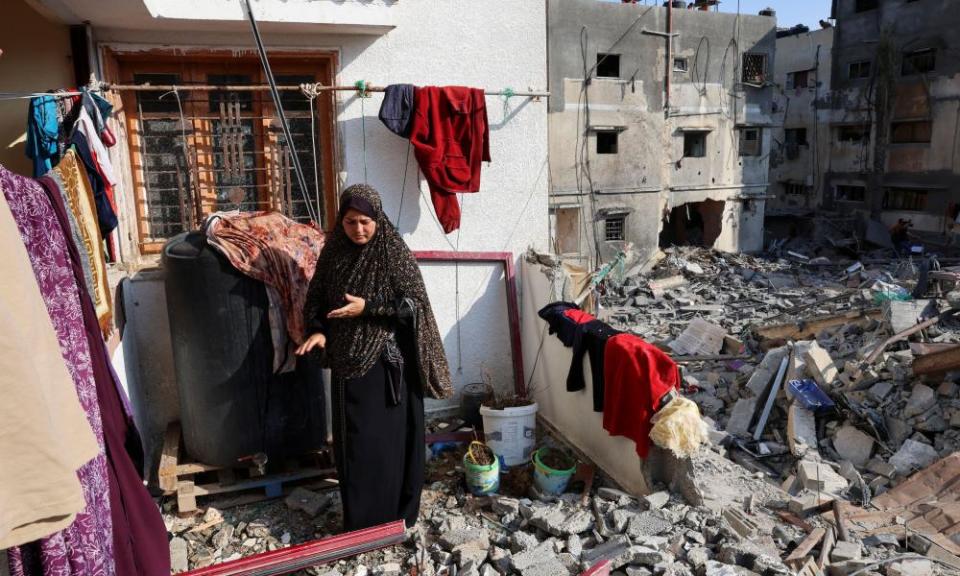 Woman outside bomb-damaged house
