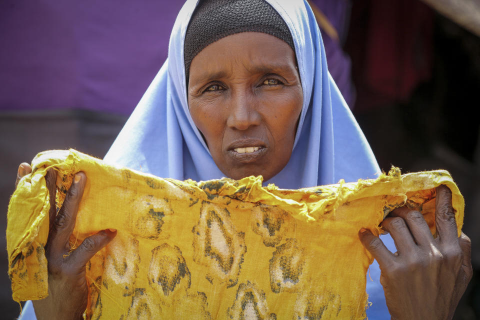 Hawa Osman Bilal shows the clothes of her daughter Ifrah, who like many vulnerable Somalis died during the difficult journey from drought-stricken areas, outside her makeshift tent at a camp for the displaced on the outskirts of Mogadishu, Somalia Thursday, June 30, 2022. The war in Ukraine has abruptly drawn millions of dollars away from longer-running humanitarian crises and Somalia is perhaps the most vulnerable as thousands die of hunger amid the driest drought in decades. (AP Photo/Farah Abdi Warsameh)