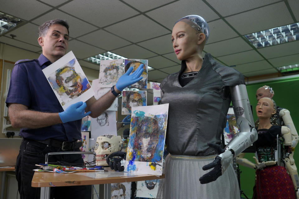 David Hanson, left, creator of Sophia, shows a work of Sophia at his studio in Hong Kong on March 29, 2021. Sophia is a robot of many talents — she speaks, jokes, sings and even makes art. In March, she caused a stir in the art world when a digital work she created as part of a collaboration was sold at an auction for $688,888 in the form of a non-fungible token (NFT).WLD(AP Photo/Vincent Yu)