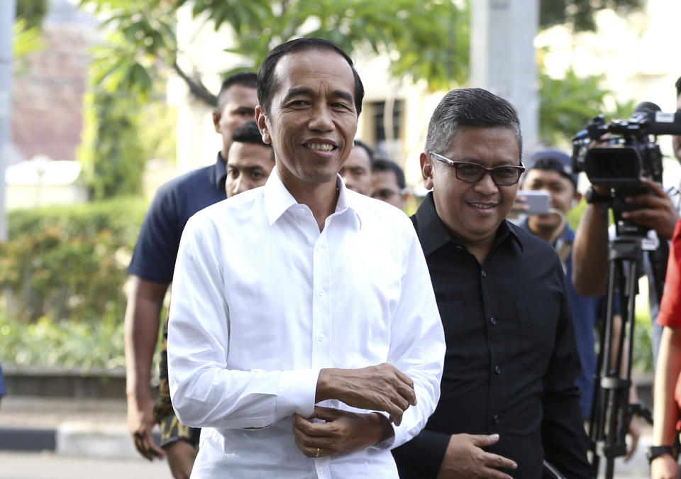 Incumbent Indonesian President Joko Widodo, center, walks with the Secretary General of Indonesian Democratic Party-Struggle Hasto Kristiyanto, right, upon arrival for a meeting with leaders of his coalition parties in Jakarta, Indonesia, Thursday, April 18, 2019. Widodo said Thursday he was won re-election after receiving an estimated 54% of the vote, backtracking on an earlier vow to wait for official results after his challenger made improbable claims of victory. (AP Photo/Achmad Ibrahim)