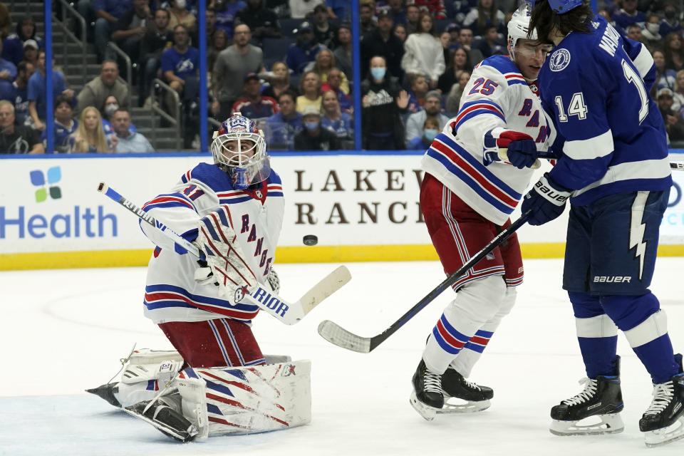 New York Rangers goaltender Igor Shesterkin (31) makes the save on a deflection by Tampa Bay Lightning left wing Pat Maroon (14) in front of defenseman Libor Hajek (25) during the second period of an NHL hockey game Friday, Dec. 31, 2021, in Tampa, Fla. (AP Photo/Chris O'Meara)
