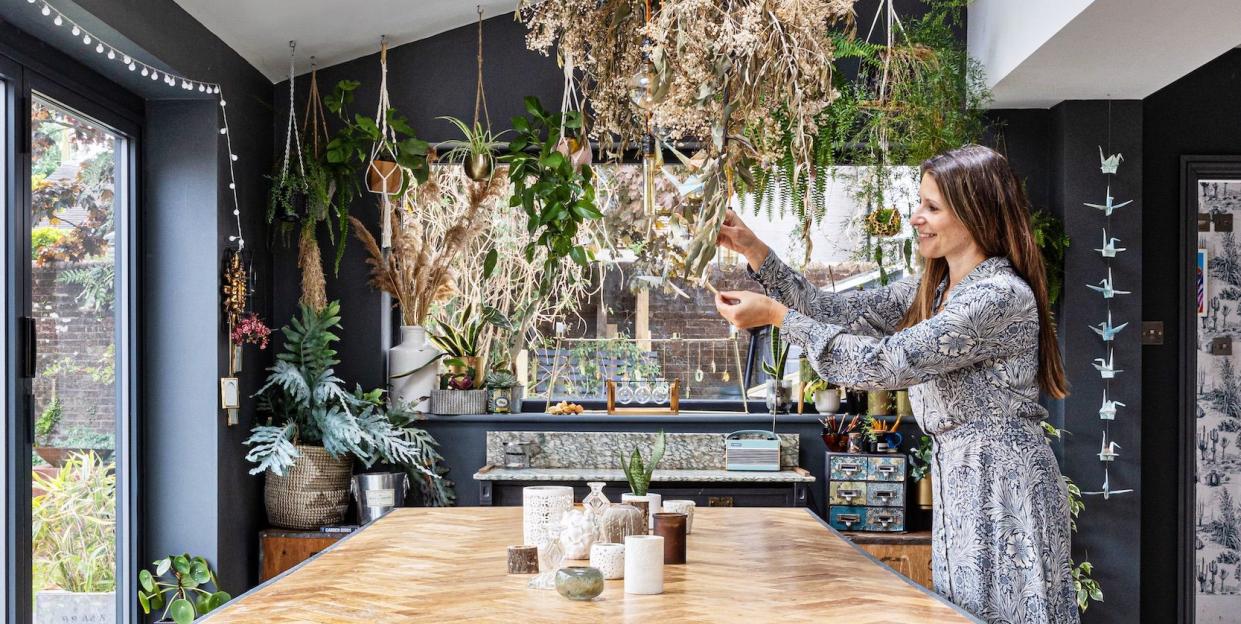 woman in kitchen tending hanging plant