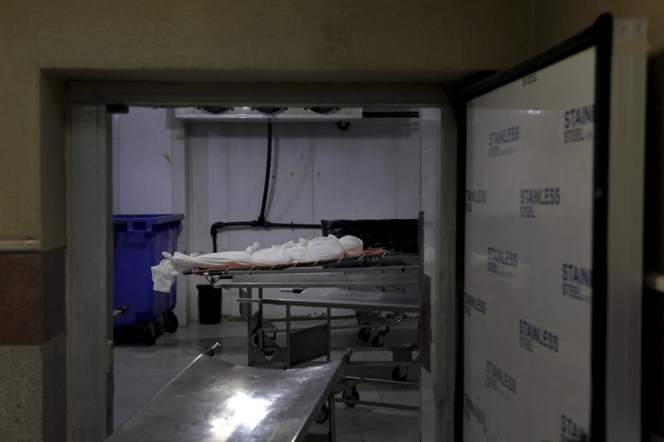 The body of a man who died from COVID-19 is prepared for a burial, at the Behesht-e-Zahra cemetery just outside Tehran, Iran, Wednesday, April 21, 2021. After facing criticism for downplaying the virus last year, authorities have put partial lockdowns and other measures in place to try and slow the coronavirus’ spread, as Iran faces what looks like its worst wave of the coronavirus pandemic yet. (AP Photo/Ebrahim Noroozi)