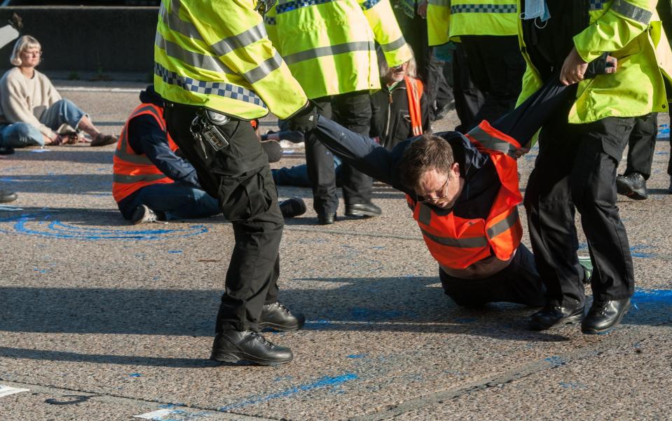 Police remove activists from the motorway as protesters from Insulate Britain block the M25 motorway near Cobham in Surrey - Guy Smallman/Getty