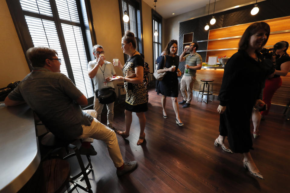 Visitors eat snacks and drink water during a media preview for the Sazerac house, in New Orleans, Tuesday, Sept. 10, 2019. Visitors to New Orleans who want to learn more about cocktails will soon have a new place to go. No, it's not another bar. The Sazerac House is a six-story building on the city's famed Canal Street owned by the Sazerac Company, a Louisiana-based spirits maker, featuring the signature New Orleans drink called the Sazerac.Tasting is encouraged, and in addition to free samples given to visitors, there will also be special classes and tastings offered daily. (AP Photo/Gerald Herbert)