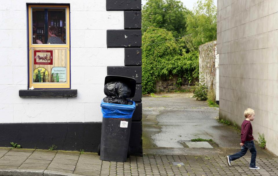 Boy walks past an empty pub, which has been covered with artwork to make it look more appealing, in the village of Bushmills on the Causeway Coast