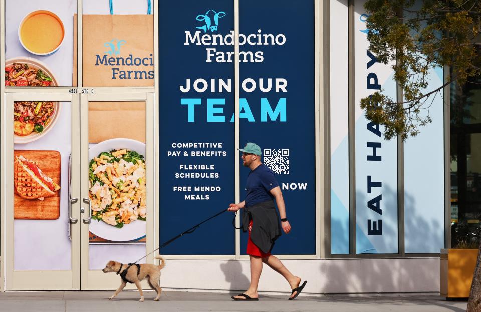 A person and dog walk past a "Join Our Team" sign posted at a restaurant which will be opening in the near future, amid a still-robust labor market, on Feb. 2, 2023 in Los Angeles, California. Unemployment benefit applications have declined to the lowest level since April 2022, with the U.S. Labor Department reporting that jobless claims fell slightly to 183,000 this week.