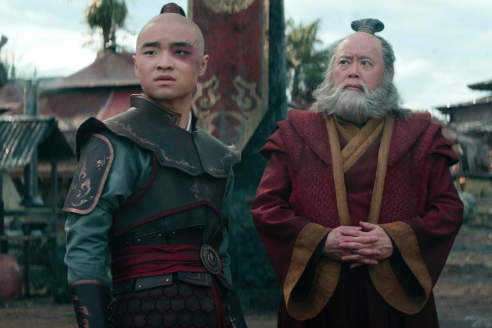 A teen boy in red-and-black armor next to an older man in red robes; Zuko and Iroh in Netflix's live-action "Avatar: The Last Airbender"