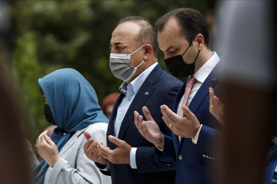 Turkish Foreign Minister Mevlut Cavusoglu, center, prays over the grave of Ahmet Sadik, who was an MP at the Greek parliament, at a muslim cemetery at Komotini town, in northeastern Greece, Sunday, May 30, 2021. Greece's prime minister said Friday his country is seeking improved ties with neighbor and longtime foe Turkey, but that the onus is on Turkey to refrain from what he called "provocations, illegal actions and aggressive rhetoric." (AP Photo/Giannis Papanikos)