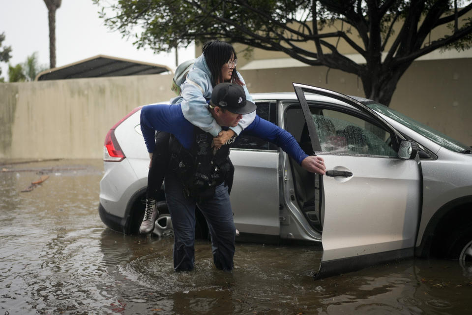 Santa Barbara Police Dept. detective Bryce Ford helps a motorist out of her car on a flooded street during a rainstorm, Thursday, Dec. 21, 2023, in Santa Barbara, Calif. (AP Photo/Jae C. Hong)