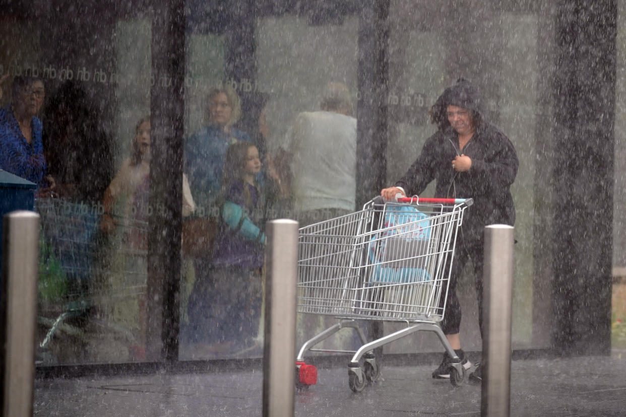 A woman is caught in heavy rain in Speke, Liverpool. Picture date: Saturday July 8, 2023. The UK is facing thunderstorms and heavy rain as forecasts that the country could see the hottest of the year were changed. (Photo by Peter Byrne/PA Images via Getty Images)