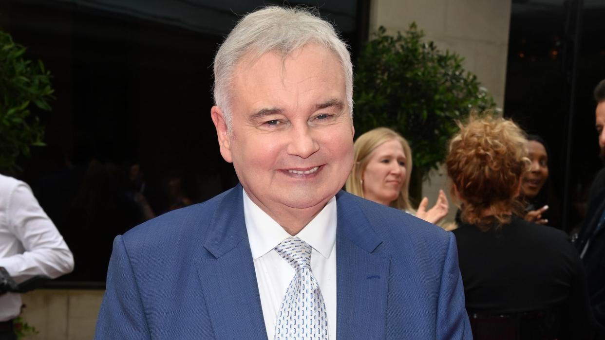 Eamonn Holmes in blue suit with crutches