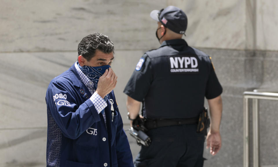 A stock trader, left, adjusts his mask as he enters the New York Stock Exchange, Thursday, July 30, 2020. Strong gains for Big Tech stocks are helping to prop up Wall Street in early Friday trading following blowout profit reports from some of the market’s most influential companies. (AP Photo/Mark Lennihan)