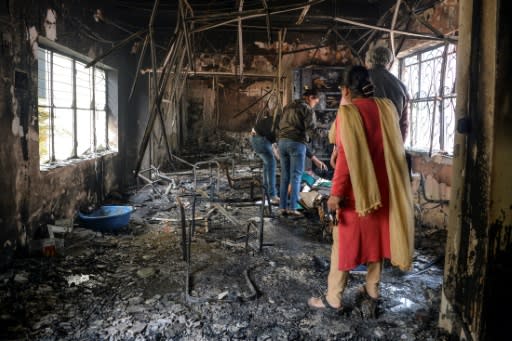 People inspect the remains of a burnt-out school premises following clashes between people supporting and opposing a contentious amendment to India's citizenship law, in New Delhi