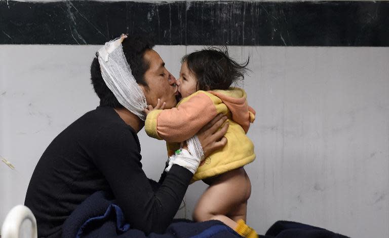 Nepalese resident Suresh Parihar plays with his 8-month-old daughter Sandhaya as he is treated for injuries sustained in an earthquake at a city hospital in Kathmandu on April 26, 2015