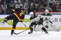 Vancouver Canucks' Brock Boeser (6) shoots the puck as Arizona Coyotes' Sean Durzi (50) and goaltender Connor Ingram (39) watch during the first period of an NHL hockey game Wednesday, April 10, 2024, in Vancouver, British Columbia. (Ethan Cairns/The Canadian Press via AP)