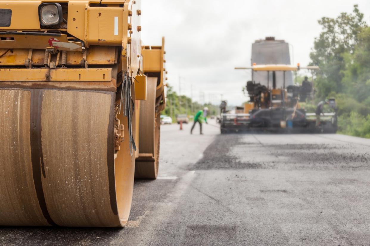 Pavers push the asphalt down during road construction. <a href="https://www.gettyimages.com/detail/photo/road-construction-works-with-roller-compactor-royalty-free-image/1023642374?phrase=road+paving&adppopup=true" rel="nofollow noopener" target="_blank" data-ylk="slk:Pramote Polyamate/Moment via Getty Images;elm:context_link;itc:0;sec:content-canvas" class="link ">Pramote Polyamate/Moment via Getty Images</a>