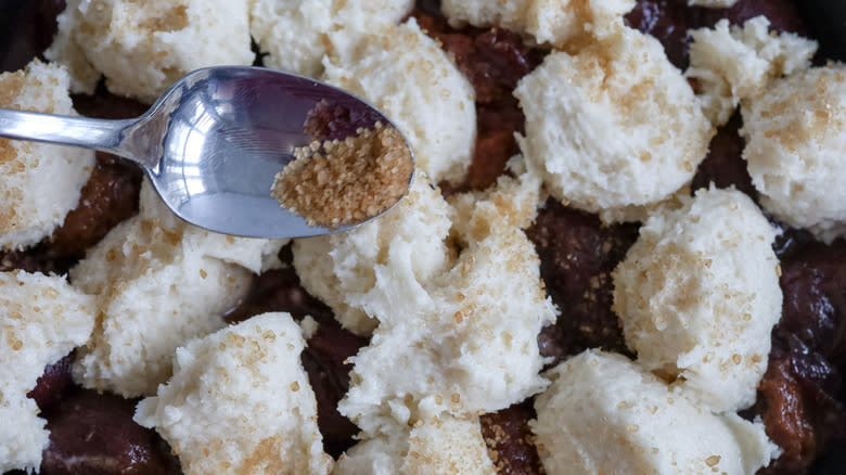 spoon sprinkling sugar onto cobbler