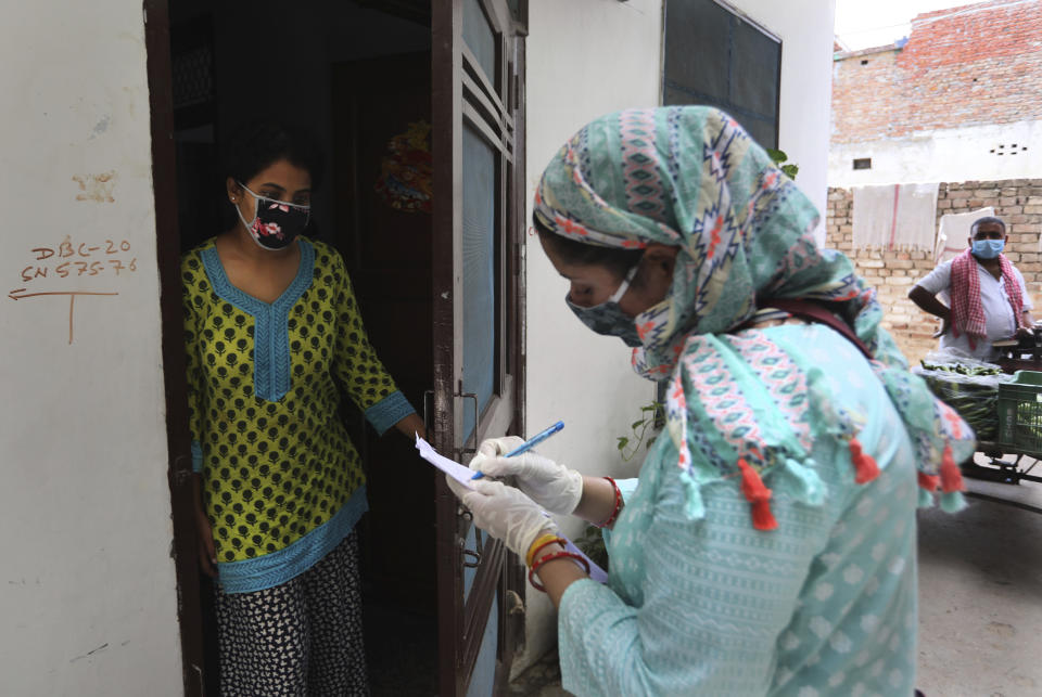 An Indian government school teacher writes down the details of a family during a survey at a residential neighborhood in New Delhi, India, Saturday, June 27, 2020. A massive survey to take down health details of New Delhi's entire population of 28 millions and test everyone with symptoms for COVID-19 started Saturday. Teams comprising of health workers and other government officials, including teachers went from home to home to conduct the survey, that is trying to screen everyone by July 6, as Delhi has become the worst hit city in India. (AP Photo/Manish Swarup)