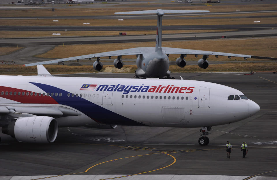 A Malaysia Airlines plane, foreground, prepares to go out onto the runway and passes by a stationary Chinese Ilyushin 76 aircraft at Perth International Airport in Perth, Australia, Tuesday, March 25, 2014. Malaysia said Tuesday that it has narrowed the search for a downed jetliner to an area the size of Texas and Oklahoma in the southern Indian Ocean, while Australia said improved weather would allow the hunt for possible debris from the plane to resume. (AP Photo/Greg Wood, Pool)