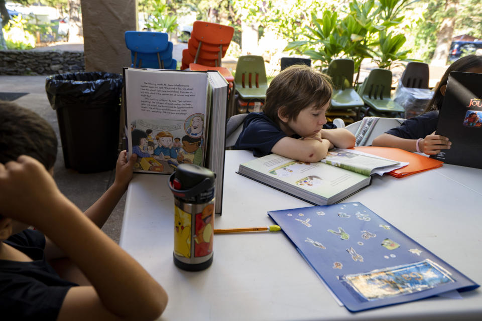 Sacred Hearts School third grade students read a book during an English language arts class at their temporary school site at Sacred Hearts Mission Church on Tuesday, Oct. 3, 2023, in Lahaina, Hawaii. The three public schools that survived the deadly August wildfire are set to reopen this week. (AP Photo/Mengshin Lin)