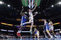 Oklahoma City Thunder guard Josh Giddey, center, shoots between Warriors forward Andrew Wiggins (22) and guard Klay Thompson, right, in the first half of an NBA basketball game Monday, Jan. 30, 2023, in Oklahoma City. (AP Photo/Sue Ogrocki)