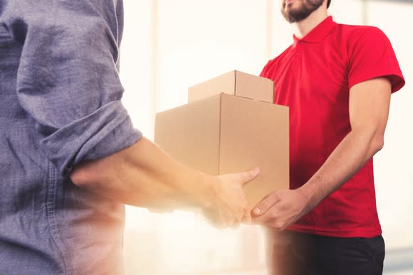 A person handing off a delivered package to someone else.