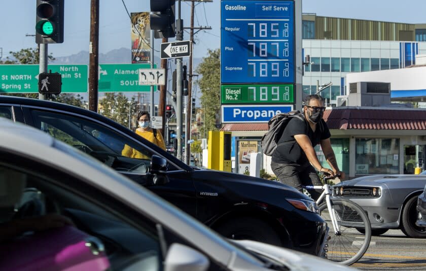 LOS ANGELES, CA-JUNE 1,2022:A bicycle rider maneuvers around motorists stuck in traffic on Cesar E. Chavez Ave., at the intersection of Alameda Street in downtown Los Angeles, where the price of gasoline approaches close to $8 a gallon at the Chevron gas station. (Mel Melcon / Los Angeles Times)