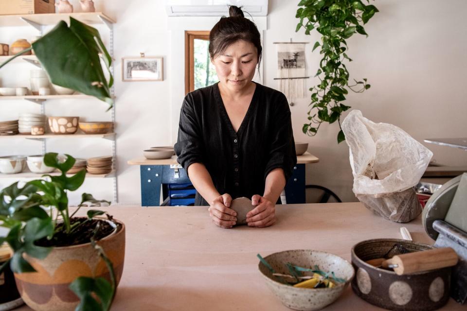 A woman molds clay with her hands