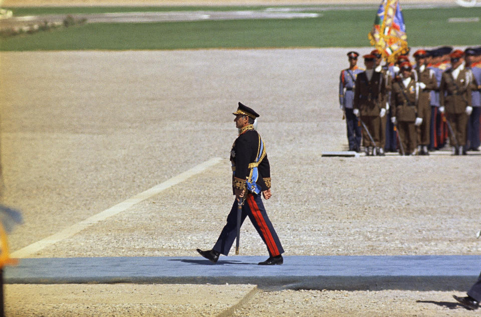 FILE - In this Oct. 13, 1971 file photo, the Shah of Iran walks to the viewing stand of visiting dignitaries, at a ceremony to mark the 2,500 anniversary of the founding of the Persian Empire, at Pasargadae, 49 miles northeast of Persepolis, Iran. At the height of his power in 1971, Pahlavi drew world leaders to a wind-swept luxury tent city in the ruins of Persepolis, offering a lavish banquet of food flown in from Paris for the celebration. (AP Photo/Horst Faas, File)