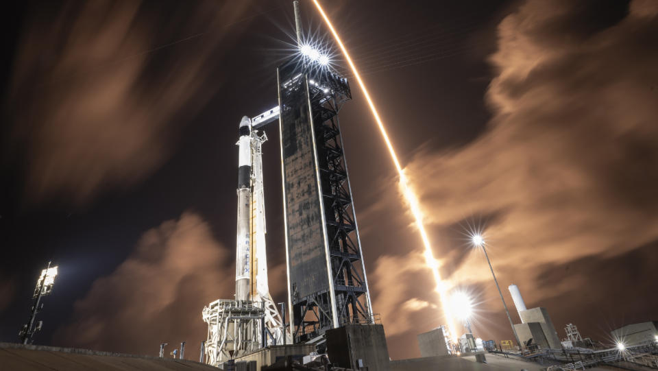  A SpaceX rocket streaks over another SpaceX rocket on the launch pad. 