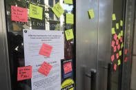 Adhesive notes are shown after they were left on the doors of Seattle Police Headquarters, Monday, July 13, 2020, following a news conference held by Mayor Jenny Durkan. Durkan and Police Chief Carmen Best spoke critically of a plan backed by several city council members that seeks to cut the police department's budget by 50 percent. (AP Photo/Ted S. Warren)