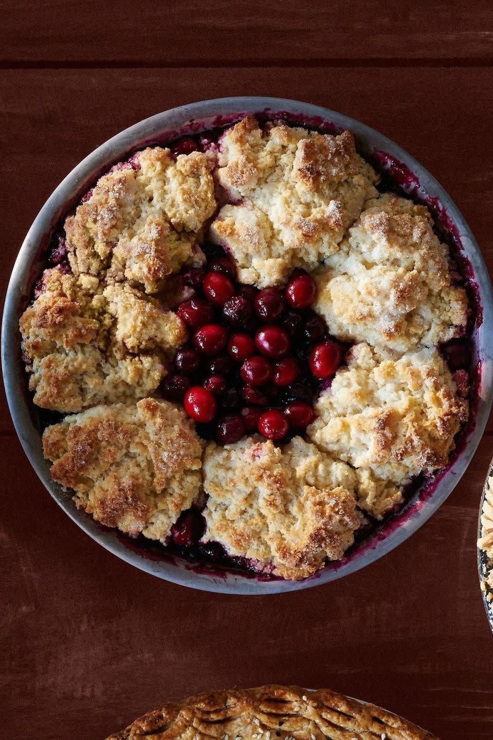 cranberry cherry cobbler pie in a metal pie tin with cranberries and cherries on top