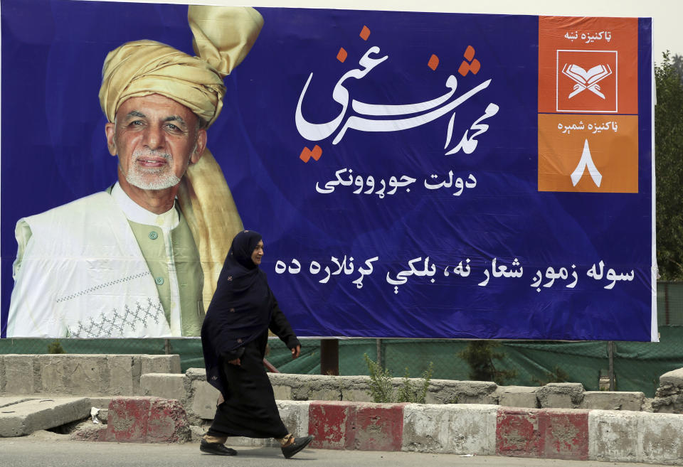 An Afghan woman walks past an election poster of a presidential candidate Ashraf Ghani during the first day of campaigning in Kabul, Afghanistan, Sunday, July 28, 2019. Sunday marked the first day of campaigning for presidential elections scheduled for Sept. 28. President Ghani is seeking a second term on promises of ending the 18-year war but has been largely sidelined over the past year as the U.S. has negotiated directly with the Taliban. (AP Photo/Rahmat Gul)
