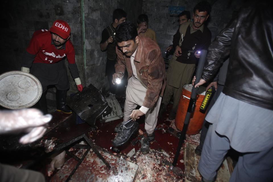 Security official and rescue workers collect evidence at the site of a bomb blast in Peshawar