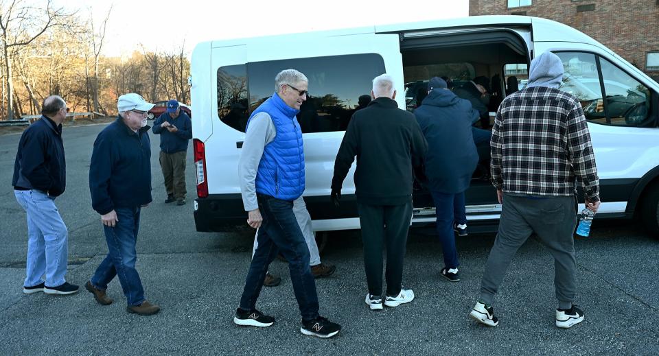 A group of former athletes and coaches from MetroWest schools board a van at the Sheraton Framingham Hotel to attend the Army/Navy football game, Dec. 9, 2022.  