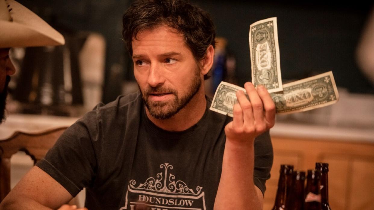  Ian Bohen as Ryan holding up three one dollar bills on Yellowstone. 