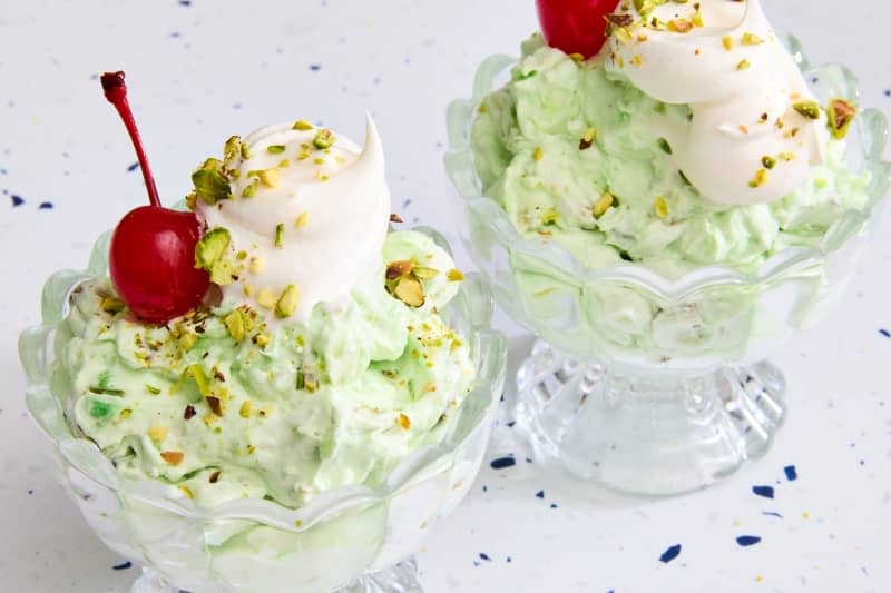 two Watergate salads with whipped cream and cherries on marble surface