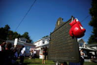 Boxing gloves are seen hanging on a historical marker outside Muhammad Ali's childhood home as mourners gather for the funeral procession for the three-time heavyweight boxing champion in Louisville, Kentucky, U.S., June 10, 2016. REUTERS/Carlos Barria