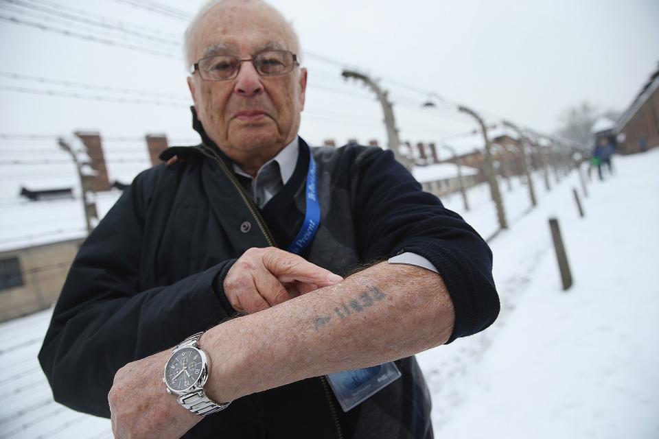 Romanian-born Jack Rosenthal, who was imprisoned at Auschwitz and other concentration camps at 14 years old, stands outside the former Auschwitz I concentration camp as he points to the number tattoo he received from the Nazis. 
