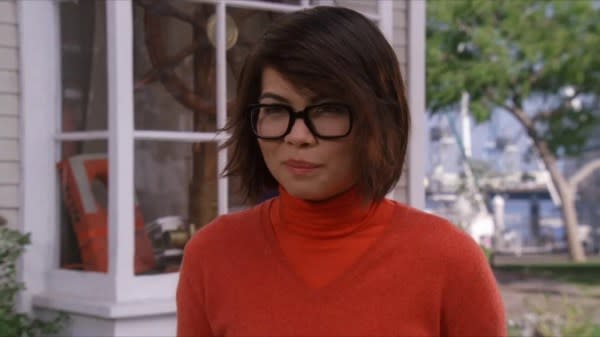 A queer Halloween costume for 2023. The image shows Hayley Kiyoko appearing as Velma from Scooby Doo, dressed in an orange jumper and wearing black glasses.